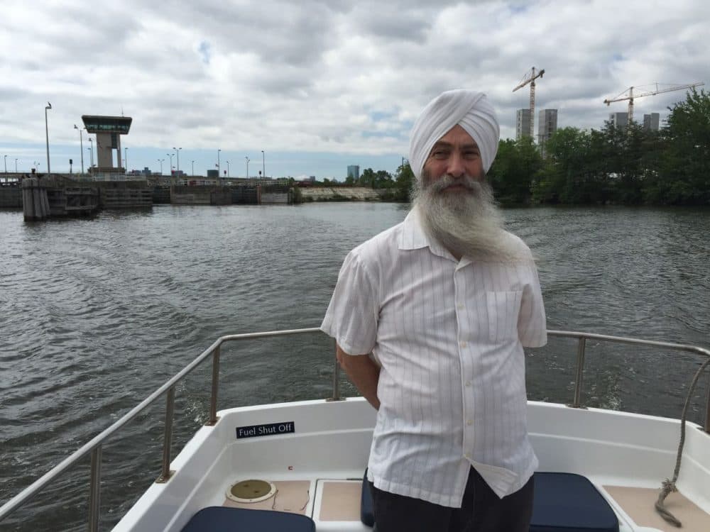 EkOngKar Singh Khalsa, executive director of the Mystic River Watershed Association, aboard a Boston Harbor Cruises water taxi on the freshwater side of the Mystic River. The Amelia Earhart Dam and Assembly Row construction is in the distance. (Anthony Brooks/WBUR)