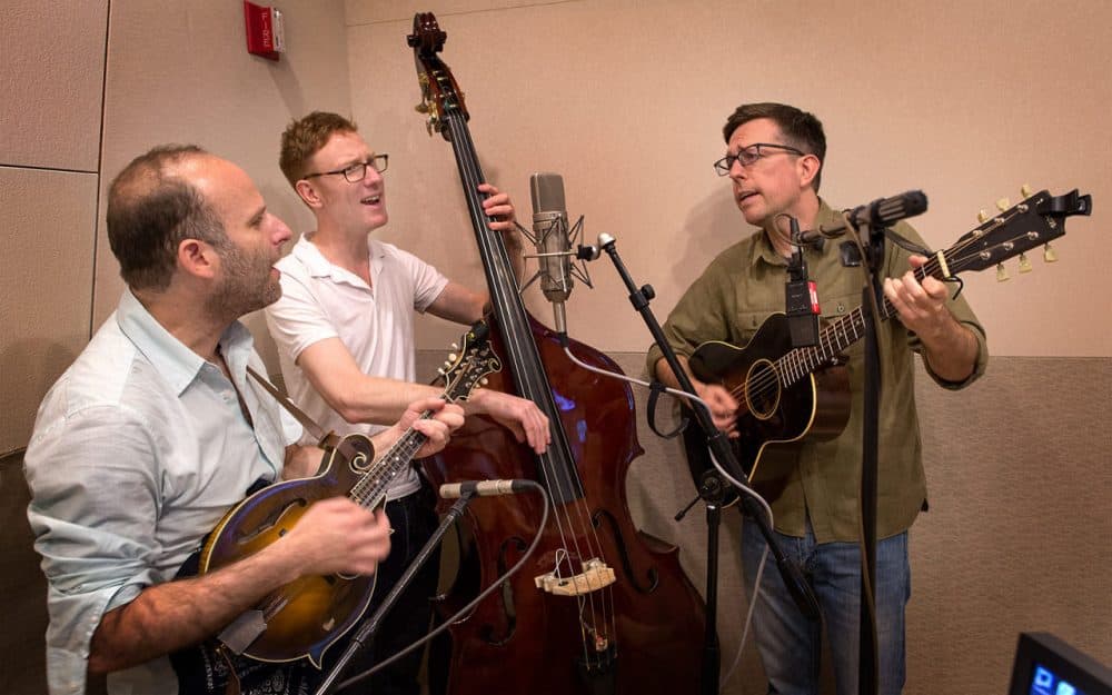 The Lonesome Trio performs in the Here &amp; Now studios. From left: Jacob Tilove on mandolin, Ian Riggs on bass and Ed Helms on guitar. (Robin Lubbock/WBUR)