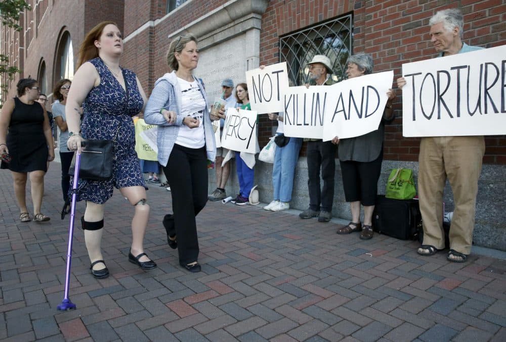 Boston Marathon bombing victim Erika Brannock and her mother Carol Downing walk past demonstrators outside federal court in Boston Wednesday. (Michael Dwyer/AP)