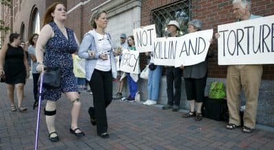 Boston Marathon bombing victim Erika Brannock, left, and her mother Carol Downing, right, walk past demonstrators outside federal court in Boston, Wednesday, June 24, 2015. (Michael Dwyer/AP)
