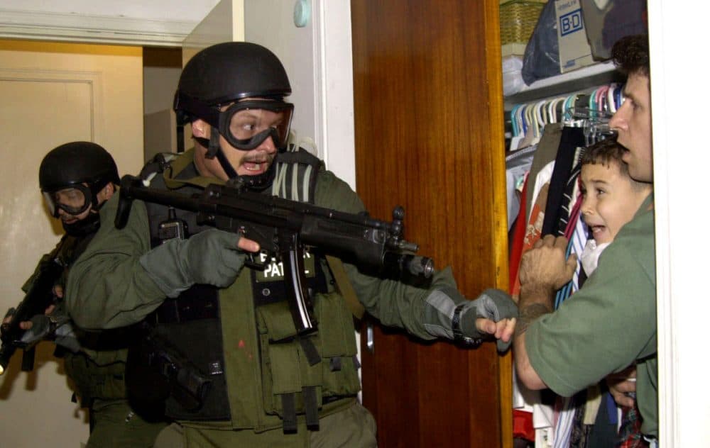 Elian Gonzalez is held in a closet by Donato Dalrymple, one of the two men who rescued the boy from the ocean, right, as government officials search the home of Lazaro Gonzalez for the young boy, early morning, April 22, 2000, in Miami, Florida. Armed federal agents seized Elian Gonzalez from the home of his Miami relatives before dawn, firing tear gas into an angry crowd as they left the scene with the weeping 6-year-old boy. (Alan Diaz/AP)