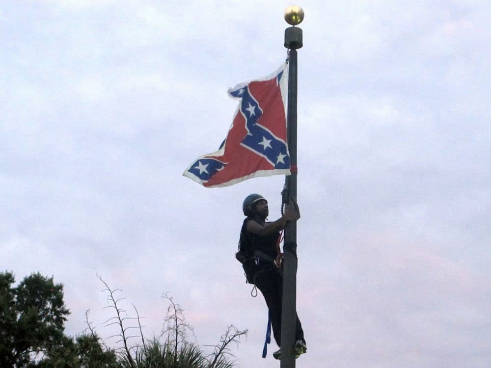 Bree Newsome of Charlotte, N.C., climbs a flagpole to remove the Confederate battle flag at a Confederate monument in front of the Statehouse in Columbia, S.C., on Saturday, June, 27, 2015. She was taken into custody when she came down. The flag was raised again by capitol workers about 45 minutes later. (Bruce Smith/AP)