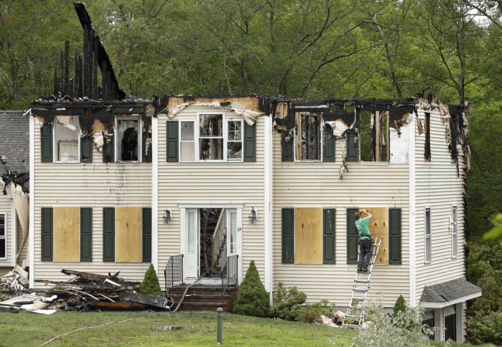 A worker stands on a ladder Monday while boarding up windows to a home that was destroyed Sunday in a small plane crash, in Plainville. (Steven Senne/AP)