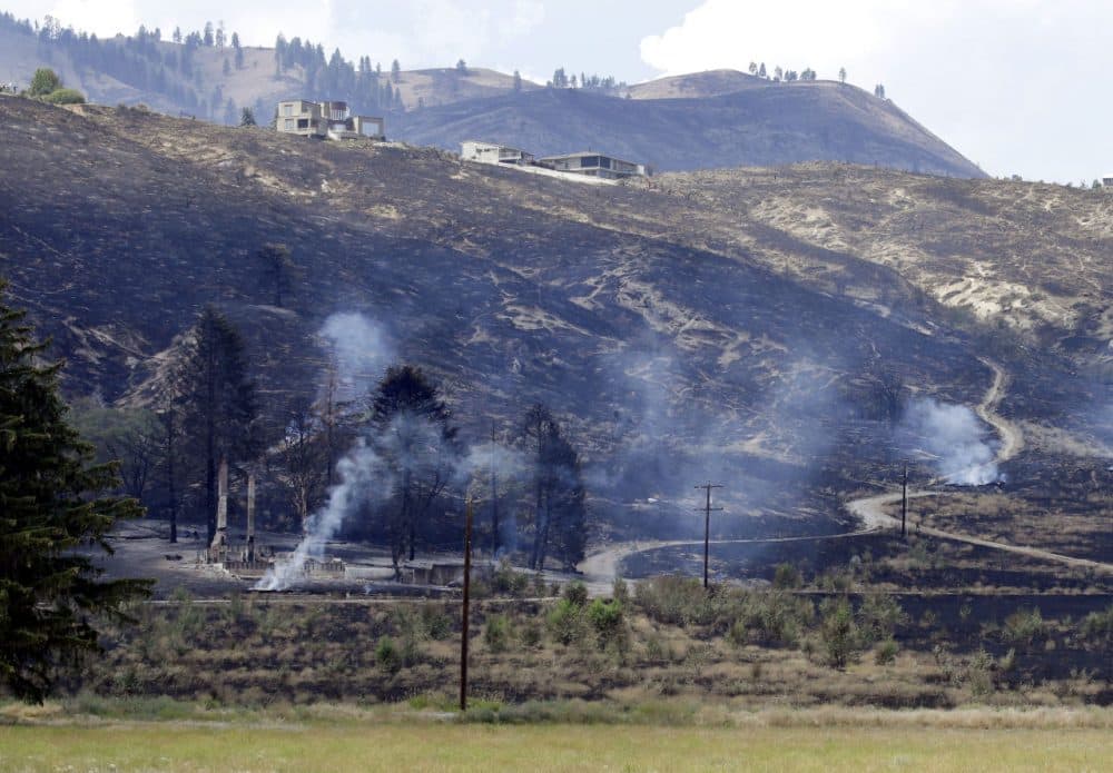 The foundation and chimneys from a destroyed home continue to smolder from a wildfire that raced through the area the night before, Monday, June 29, 2015, in Wenatchee, Wash. (Elaine Thompson/AP)