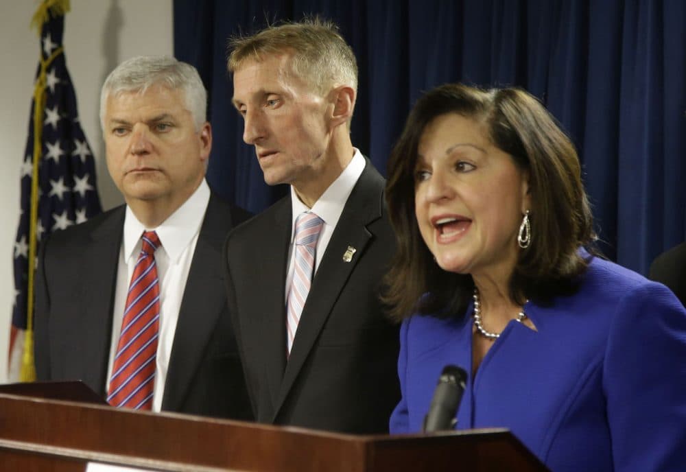 U.S. Attorney Carmen Ortiz, right, speaks alongside Suffolk District Attorney Daniel Conley, left, and Boston Police Commissioner William Evans, during a news conference Thursday in Boston. Federal authorities say 48 members and associates of Boston's most powerful gang have been indicted on drug and gun charges. Seven remain at large. (Stephan Savoia/AP)
