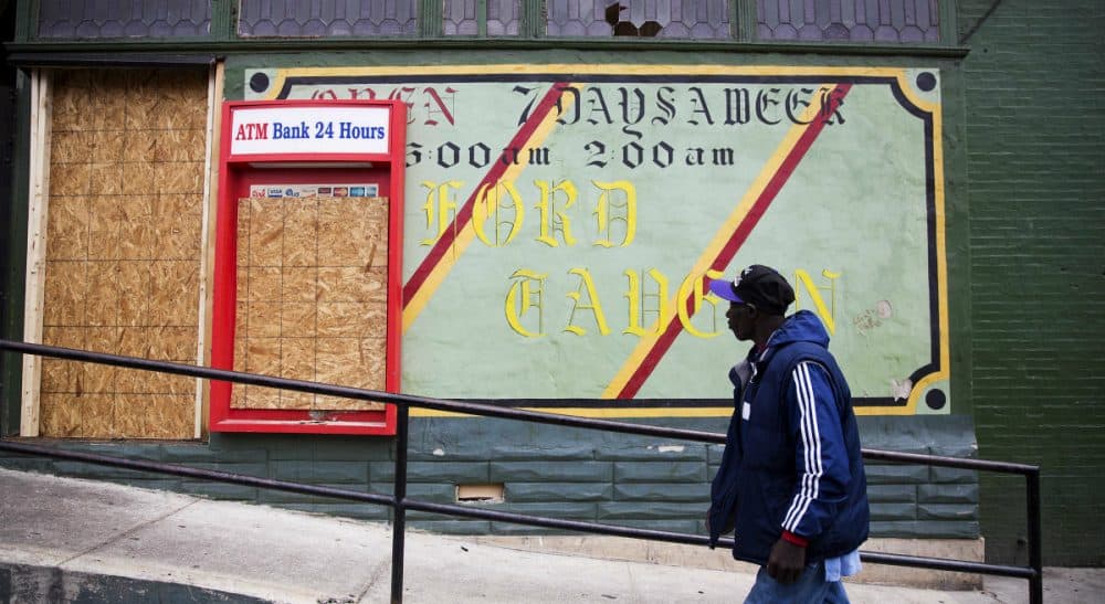 A man walks past the damaged Oxford Tavern in Baltimore, MD, on April 30, 2015. In a presidential campaign where candidates are jockeying to be champions of the middle class and courting donations from the wealthy, the poor are inching their way into the debate. Systemic problems have trapped many of the 45 million Americans living in poverty. But addressing the economic, education and security issues that have plagued underprivileged regions of America for decades remains a politically elusive challenge. (David Goldman/AP)