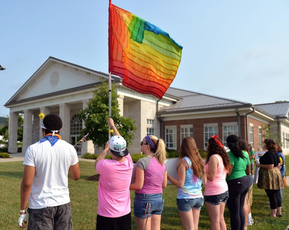 Protesters waive a rainbow flag on the front lawn of the Rowan County Judicial Center, Tuesday, June 30, 2015, in Morehead, Ky. The protest was being held against Rowan County Clerk Kim Davis, who, due to the ruling of the Supreme Court of the United States and her own religious beliefs, has refused to issue any marriage licenses in the county. (Timothy D. Easley/AP)