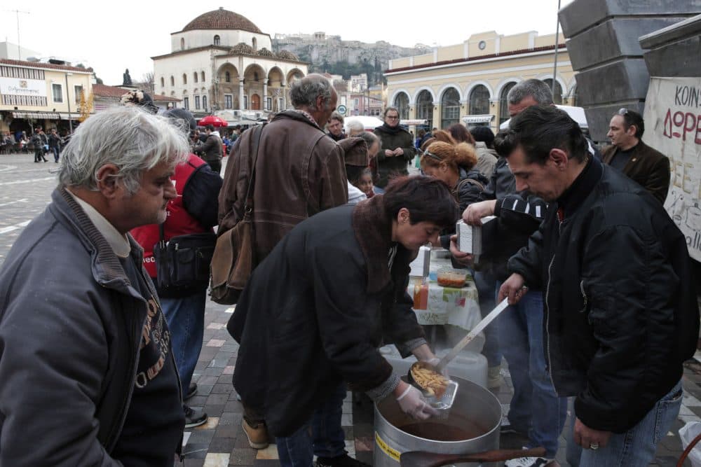 This photo taken on Tuesday, Jan. 20, 2015 shows volunteers from a soup kitchen serving food to people, in Athens. Greece goes to the polls Sunday, Jan. 25, 2015 with voters given a tough choice over how to handle the country’s staggering national debt after six years of recession badly weakened its economy. The popular left-wing Syriza party is poised to defeat conservative Prime Minister Antonis Samaras, after campaigning on demands that other eurozone countries forgive at least half the bailout loan money received since 2010. (Lefteris Pitarakis/AP)