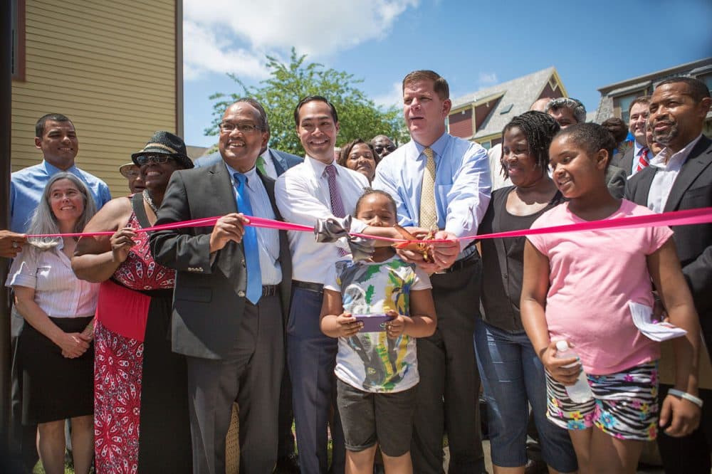 Mayor Marty Walsh,  U.S. Housing Secretary Julián Castro, City Councilor Charles Yancey and members of the community prepare to cut the ribbon during a ceremony at the new Quincy Heights housing development in Dorchester Tuesday. The new development is also home to a 35,000-square-foot shared food production facility. (Jesse Costa/WBUR)