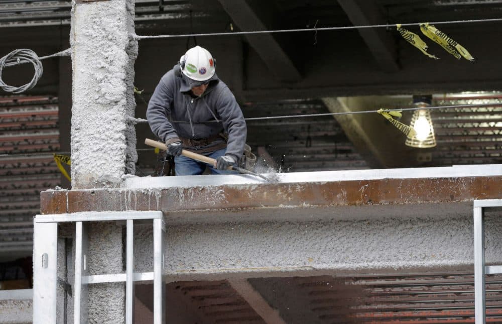 In this 2014 file photo, a worker scrapes an iron girder at a building construction site in Boston. (Steven Senne/AP)