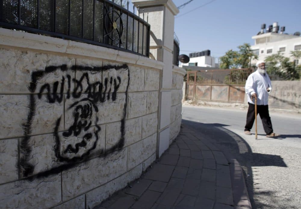 A Palestinian man walks past a graffiti portraying the Islamic State group's flag in the East Jerusalem neighbourhood of Beit Hanina on July 5, 2015. (Ahmad Gharabli/AFP/Getty Images)