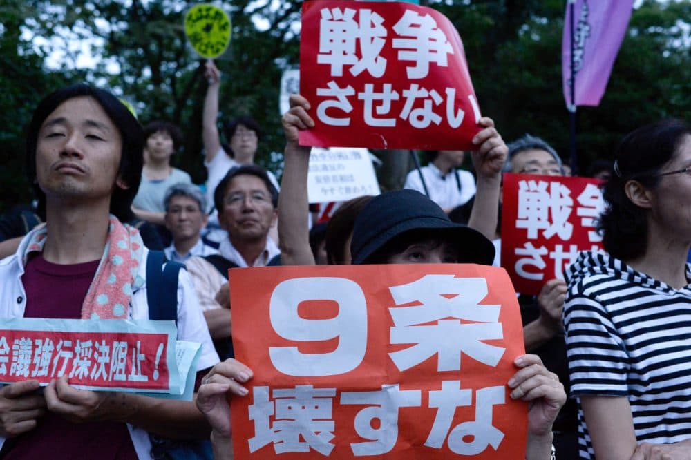 People hold signs during a protest outside the National Diet on July 16, 2015 in Tokyo, Japan. The protest is against the security bill approved by the Lower House on July 16, 2015, that would allow Japan's Self Defense Forces to also defend aggression against its allies - a concept called collective self-defense, pushed by leading Liberal Democratic Party despite the surging opposition by lawmakers and ordinary voters. (Takashi Aoyama/Getty Images)