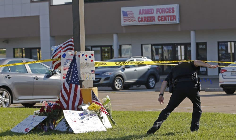 A police officer ducks under tape near a memorial in front of an Armed Forces Career Center on Thursday, July 16, 2015, in Chattanooga, Tenn. (John Bazemore/AP)