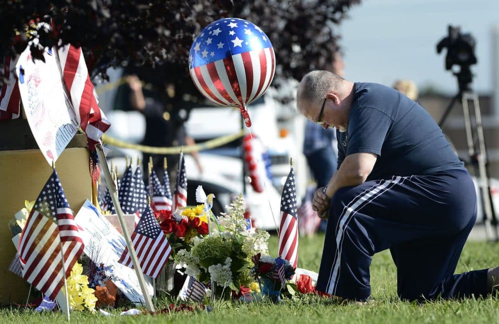 Bill Lettmkuhl kneels by a makeshift memorial in front of near the Armed Forces Career Center on Friday in Chattanooga, Tenn. Muhammad Youssef Abdulazeez, of Hixson, Tenn., attacked two military facilities on Thursday, in a shooting rampage that killed four Marines. (Mark Zaleski/AP)