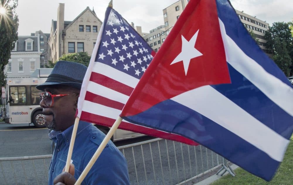 A man waves the U.S. and Cuban flags as he walks in front of the new Cuban Embassy shortly before its official ceremonial opening July 20, 2015, in Washington, D.C. (Paul J. Richards/AFP/Getty Images)