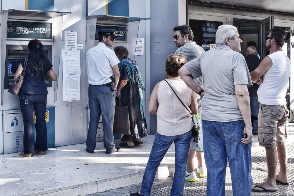 A policeman stands guard as people queue to get money from ATMs as Greek banks reopened on Monday morning after three weeks of closure on July 20, 2015 in Athens, Greece. (Milos Bicanski/Getty Images)