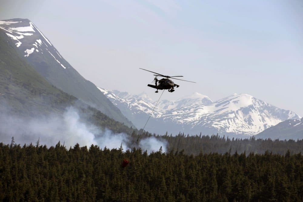 In this June 17, 2015 photo from the Alaska Army National Guard, a “Bambi Bucket,” hanging from an ANG Black Hawk helicopter releases hundreds of gallons of water onto the Stetson Creek Fire near Cooper Landing, Alaska. (Sgt. Balinda O’Neal/U.S. Army National Guard via AP)