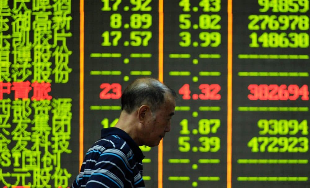 An investor walks past a screen that shows share prices in a security firm in Hangzhou, east China's Zhejiang province on July 27, 2015.  China's benchmark Shanghai stock index slumped 5.22 percent in afternoon trade on July 27, dragged lower by worries over the economy.    AFP PHOTO    CHINA OUT        (STR/AFP/Getty Images)