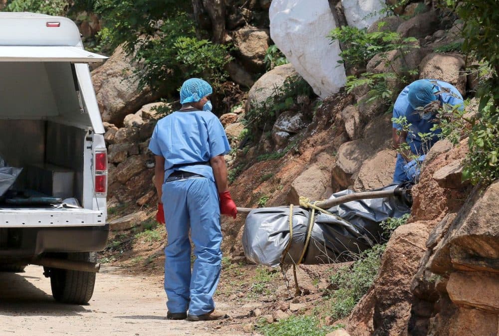 Forensic personnel load onto a van the body of one of the 10 bodies found in clandestine graves in the tourist city of Acapulco, Guerrero State on June 22, 2015. Guerrero is one of Mexico's poorest and most violent states, where a lucrative drug trade has flourished. (STR/AFP/Getty Images)