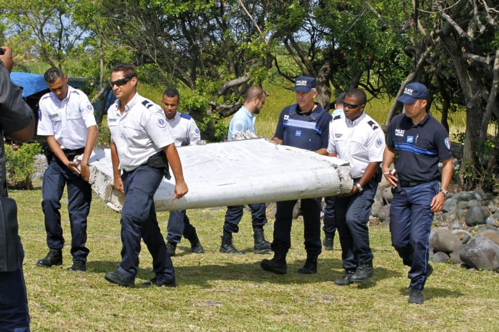 French police officers carry a piece of debris from a plane in Saint-Andre, Reunion Island on Wednesday, July 29, 2015. Air safety investigators, one of them a Boeing investigator, have identified the component as a &quot;flaperon&quot; from the trailing edge of a Boeing 777 wing, a U.S. official said. Flight 370, which disappeared March 8, 2014, with 239 people on board, is the only 777 known to be missing. (Lucas Marie/AP)