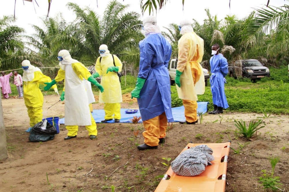 The wrapped remains of a new born child suspected of contracting the Ebola virus, lays on a stretcher as health workers, dressed in Ebola protective gear, move the body for burial in Dubreka, Guinea on June 19. (Youssouf Bah/AP)