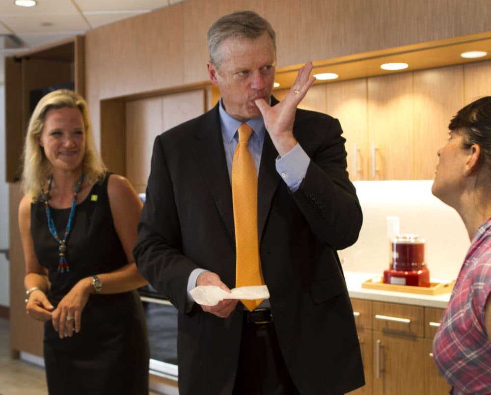 Gov. Charlie Baker enjoys a donut from Union Square Donuts at the opening of the Boston Public Market opening this week. (Hadley Green/WBUR)