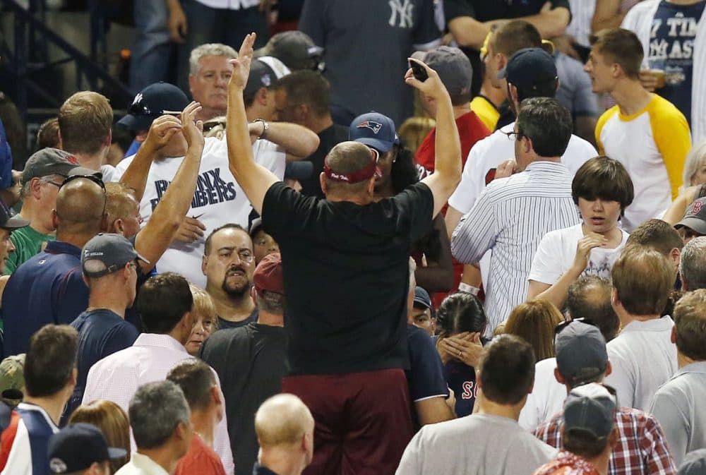A woman, lower right, holds her head after being hit by a foul ball during the fifth inning of Friday night's Red Sox-Yankees game at Fenway Park. (Michael Dwyer/AP)