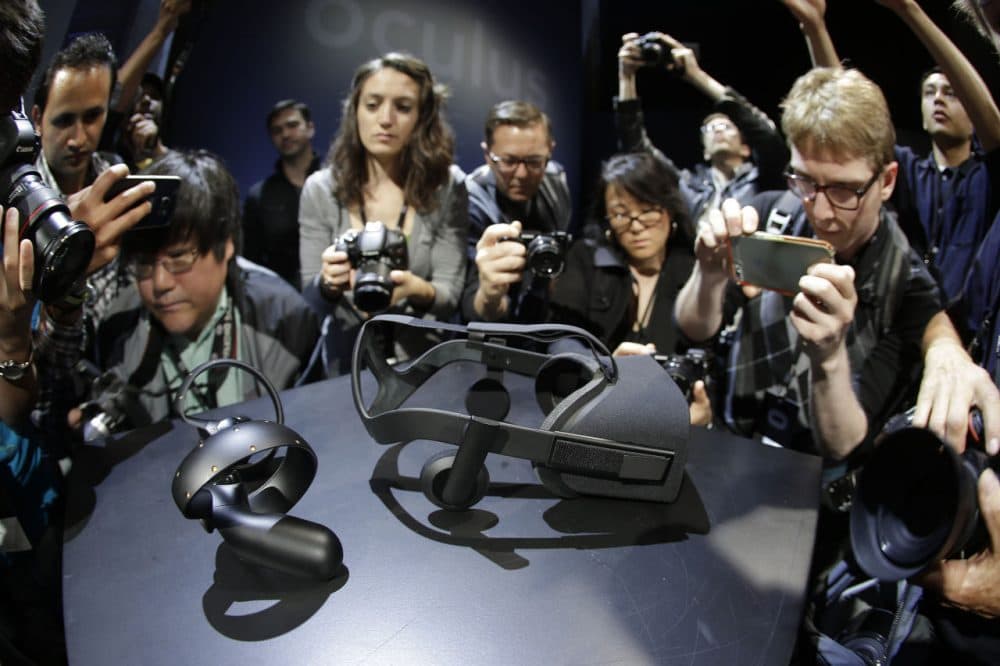 Photographers take pictures of the new Oculus Rift virtual reality headset and touch input device following a news conference Thursday, June 11, 2015, in San Francisco. (AP Photo/Eric Risberg)
