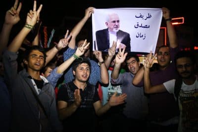 Young Iranian men cheer and show victory sign with a picture of Foreign Minister Mohammad Javad Zarif, reading &quot;Zarif is Mosaddegh of our time,&quot; comparing Zarif to Mohammad Mosaddegh, Iran's legendary prime minister during the 1950s who nationalized the country's oil industry, in Tehran, Iran, Tuesday, July 14, 2015. (AP)
