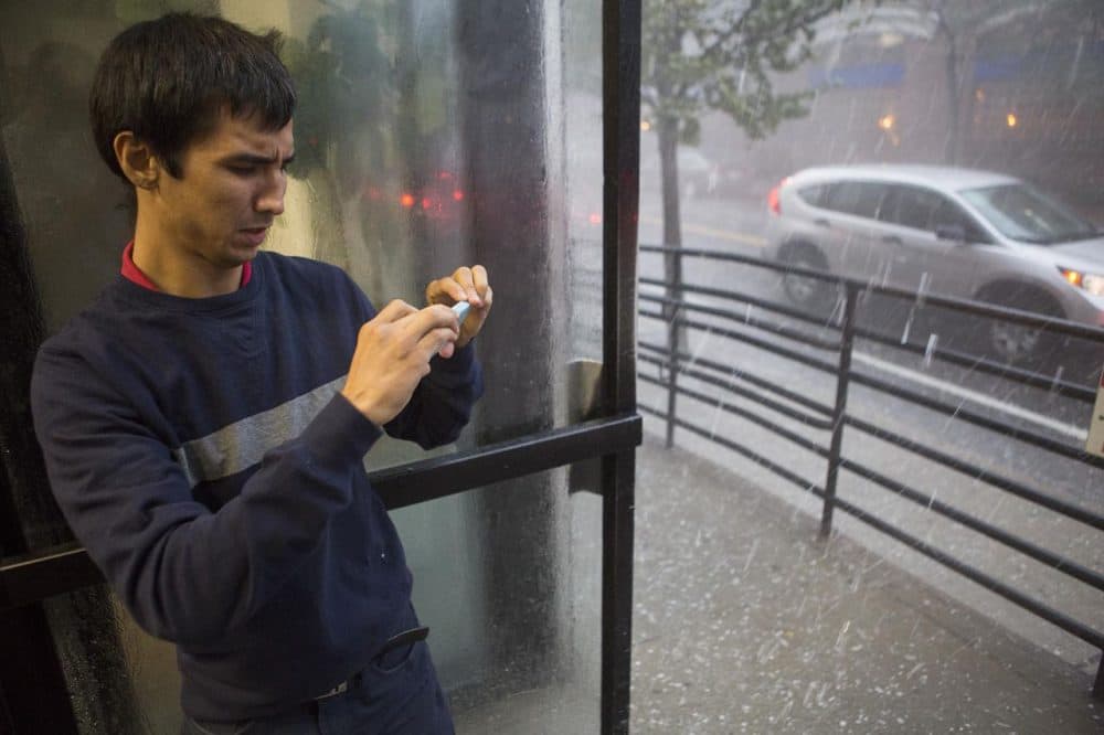 A man takes a photo of the hail falling outside on St. Paul Street in Boston Tuesday. (Jesse Costa/WBUR)