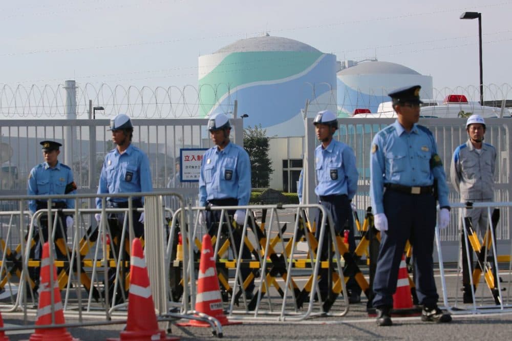 Police officers and security personnel stand in front of the gate of the Kyushu Electric Power Sendai nuclear power plant as anti-nuclear protesters rally against the restarting of the nuclear reactor in Satsumasendai, Kagoshima prefecture, on Japan's southern island of Kyushu yesterday.  Japan restarted a mothballed nuclear reactor for the first time in two years since the Fukushima meltdown. (Jiji Press/Getty Images)