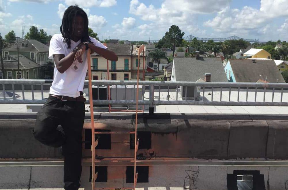 Kendall Hooker stands on the roof of the New Orleans Healing Center in the city's Marigny neighborhood. Behind him is the edge of the skyline, and the Crescent City Connection Bridge. (Laine Kaplan-Levenson)