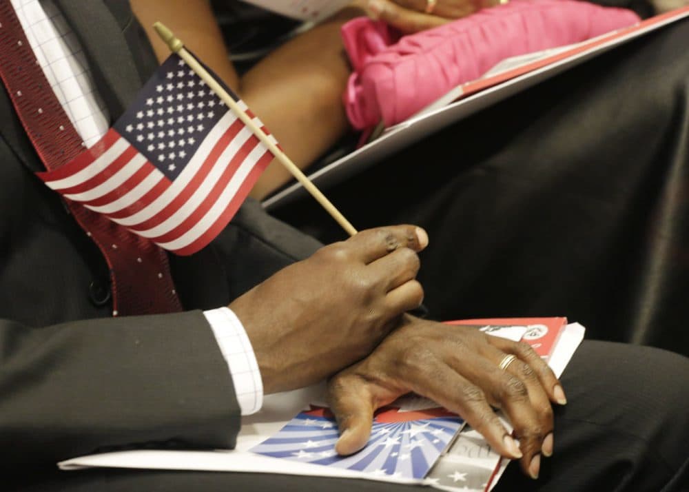 A new United States citizen holds an American flag during a naturalization ceremony, Wednesday, July 9, 2014 in New York. (Mark Lennihan/AP)