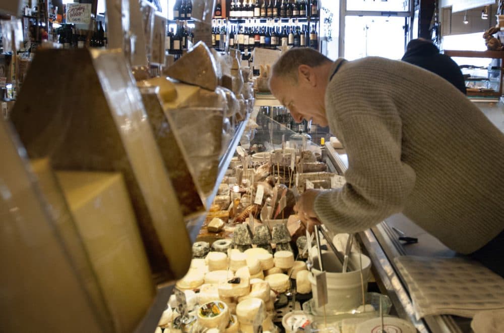 Formaggio Kitchen owner Ihsan Gurdal looks through the cheese case at the Cambridge store. Gurdal used to coach volleyball at Harvard before buying Formaggio Kitchen in the early 1990s. (Andrea Shea/WBUR)