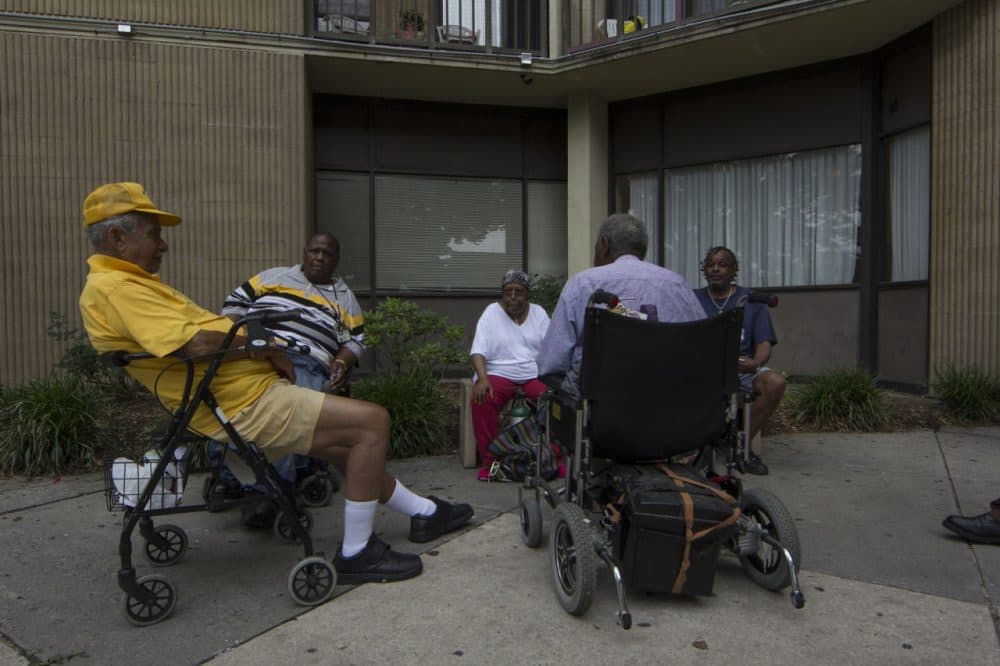 A group of friends sit in front of Bel Park Towers in Park Heights. Many of the folks in this picture spent a lot of time telling me about their concerns and the conditions of their building. (Jonna McKone/ WYPR)