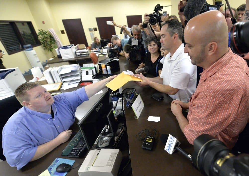 Rowan County deputy clerk Brian Mason, left, hands James Yates, and his partner William Smith Jr., their marriage license at the Rowan County Judicial Center in Morehead, Ky., Friday, Sept. 4, 2015. After four attempts, Yates and Smith were finally issued their marriage license. (Timothy D. Easley/AP)