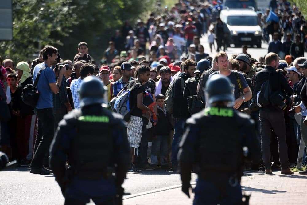 Hungarian riot police officers stand in front of migrants at a collection point at Roszke village at the Hungarian-Serbian border on September 9, 2015. Some 400-500 migrants on Wednesday broke through police lines in Hungary near the main crossing point from Serbia, AFP reporters at the scene said. (Attila Kisbenedek/AFP/Getty Images)