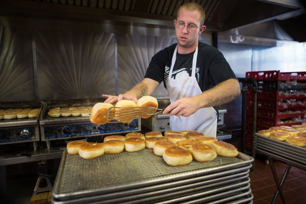 Stone & Skillet's Joe Howland takes hot English muffins off the griddle to cool. (Jesse Costa/WBUR)