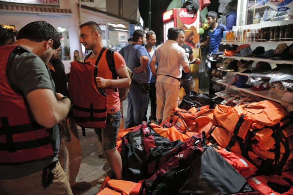 Syrian migrants planning to cross onto boats to the nearby Greek island of Kos, try on life jackets offered for sale outside a tourist shop in the coastal town of Bodrum, Turkey, Thursday, Aug. 13, 2015. (Lefteris Pitarakis/AP)