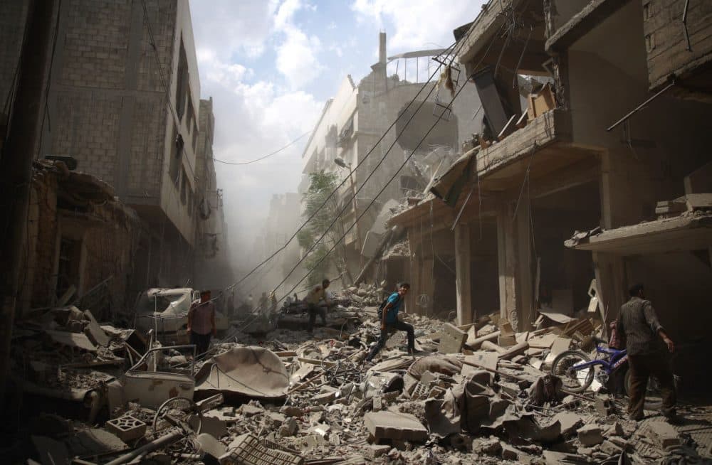 Syrians walk amid the rubble of destroyed buildings following reported air strikes by regime forces in the rebel-held area of Douma, east of the capital Damascus, on August 30, 2015. More than 240,000 people have been killed since Syria's conflict began in March 2011, and half of the country's population has been displaced by the war.  (ABD Doumany/Getty Images)