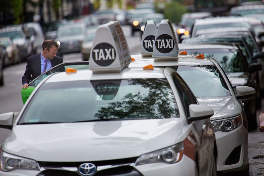 A man jumps into one of a line of taxis at a taxi stand on Boylston Street. (Jesse Costa/WBUR)