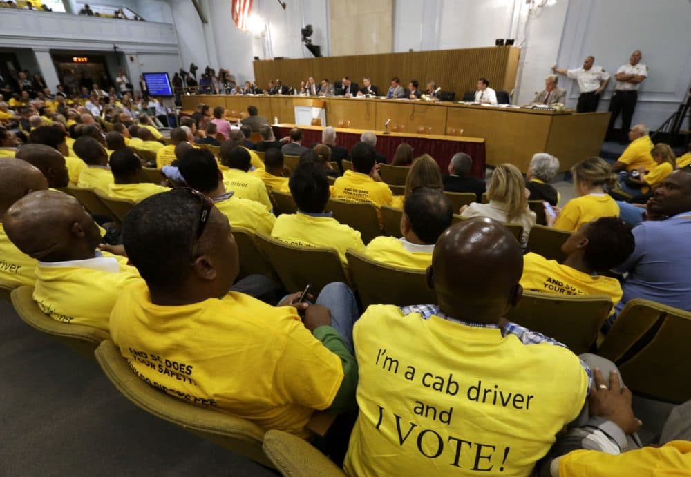 Taxi drivers wearing yellow T-shirts sit together during a hearing on the regulation of ride-hailing companies such as Uber and Lyft, at the State House in Boston last month. (Steven Senne/AP)