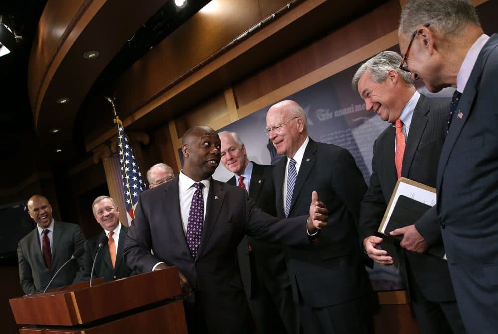 Sen. Tim Scott (C) (R-SC) jokes with Democratic senators including Sen. Sheldon Whitehouse (2nd R) (D-RI) during a press conference at the U.S. Capitol announcing a bipartisan effort to reform the criminal justice system. (Win McNamee/Getty Images)