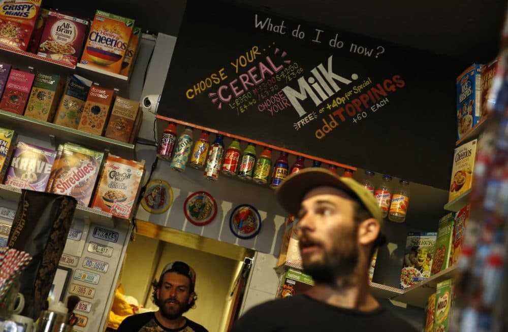 A member of staff of the Cereal Killer Cafe helps point out to a customer the range of cereals available, from U.S. favorites to European gluten free organics, at the cafe in Brick Lane, London, Wednesday, Sept. 30, 2015. The Cereal Killer Cafe has drawn both derision and big crowds since it opened nine months ago, offering a cornucopia of flakes, pops and puffs from about 3 pounds ($4.50) a bowl. Now it has attracted the ire of anti-gentrification protesters, who last week surrounded the business with flaming torches and scrawled &quot;scum&quot; on its windows as customers sheltered in the basement. (Alastair Grant/AP)