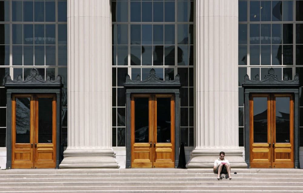 A doctoral student at MIT reads outside a building at the Cambridge campus. (Michael Dwyer/AP File)