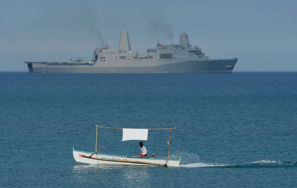A Filipino fisherman is seen past the U.S. Navy amphibious transport dock ship USS Green Bay (LPD-20) during an amphibious landing exercise on a beach at San Antonio in Zambales province on April 21, 2015, as part of annual Philippine-US joint maneuvers some 220 kilometres (137 miles) east of the Scarborough Shoal in the South China Sea. The Philippines voiced alarm April 20 about Chinese 'aggressiveness' in disputed regional waters as it launched giant war games with the United States that were partly aimed as a warning shot to Beijing. AFP PHOTO/TED ALJIBE (Ted Alijbe/AFP/Getty Images)