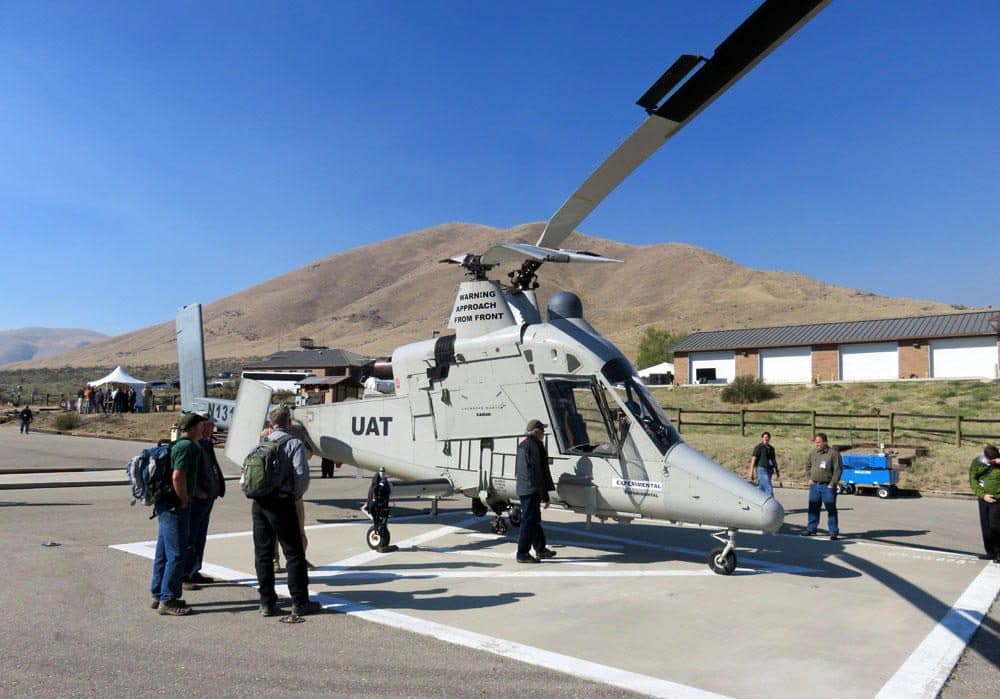 Federal firefighting managers peruse the ''optionally-piloted'' K-MAX helicopter at the Lucky Peak Helibase in Idaho. &quot;UAT&quot; on the fuselage stands for Unmanned Aerial Truck. (Tom Banse/Northwest News Network)