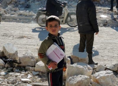 A Syrian boy holds books as he stands outside his school following airstrikes by Syrian government forces on December 22, 2013 in the northern Syrian city of Marea on the outskirts of Aleppo. (Mohammed Al-Khatieb/AFP/Getty Images)
