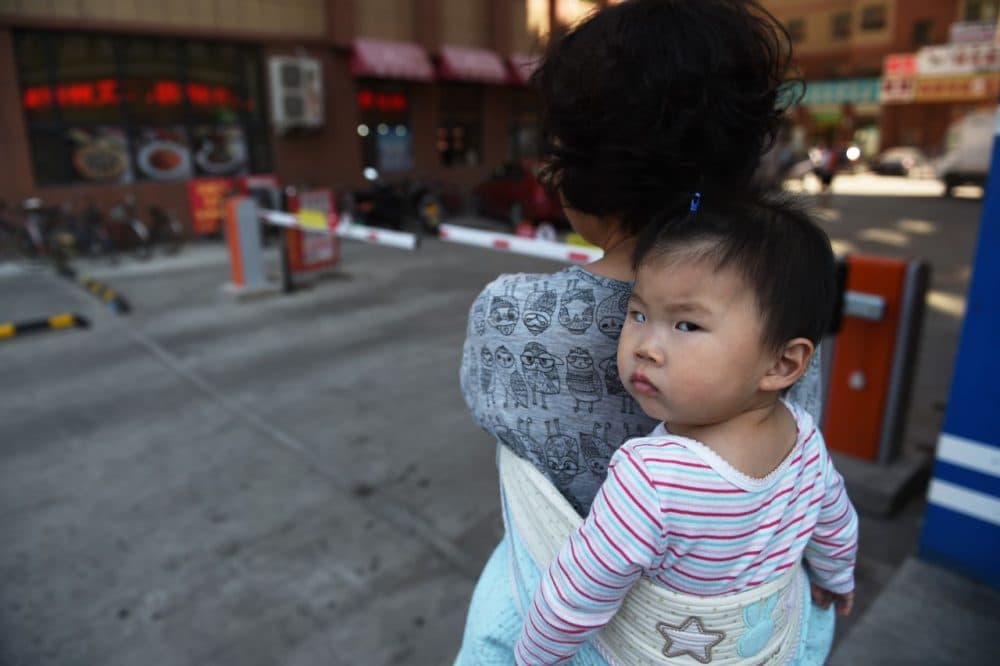 A woman carrying a baby in Yanji, in China's northeast Jilin province. China's Communist leaders gather on October 26 to hash out a new Five Year Plan to battle slowing growth, and analysts say they must choose between such outmoded concepts as GDP targets and reforms that could include the one-child policy.   (Greg Baker/AFP/Getty Images)