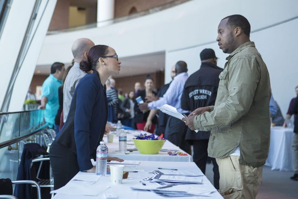 A former inmate inquires about job programs from one of the many vendors at a community resource fair at the Moakley courthouse in Boston Wednesday, hosted by the U.S. Probation and Pretrial Office. (Jesse Costa/WBUR)